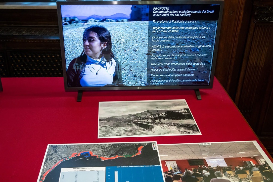 I materiali dell'indagine Palermo da costa a costa sul tavolo: lo schermo con l'elenco delle proposte, la fotografia storica della costa e l'ortofoto con l'analisi del degrado