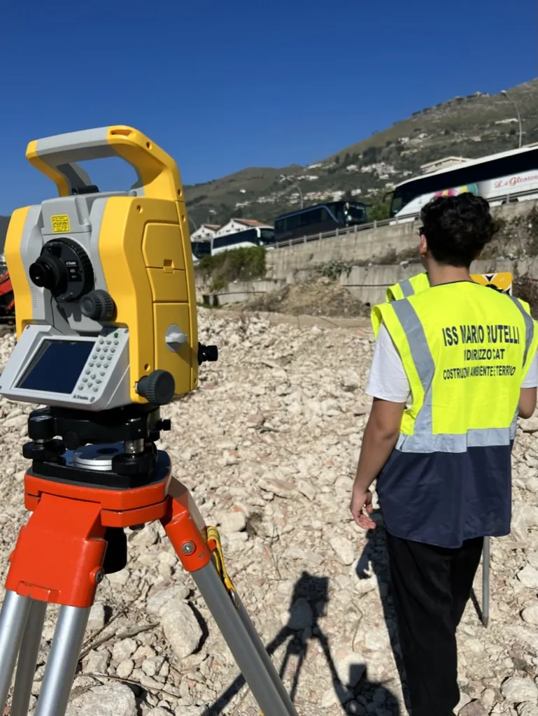 Stazione totale montata su treppiede durante un rilievo topografico sul campo
