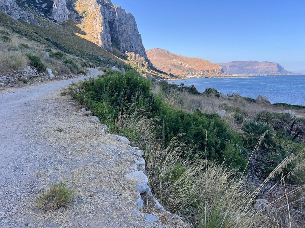 Il sentiero sterrato della riserva di Capo Gallo, con una parete di roccia calcarea a sinistra e il mare a destra