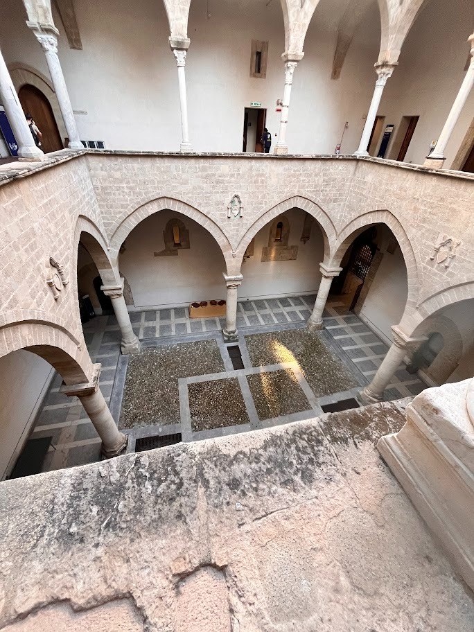 Il cortile di Palazzo Chiaramonte-Steri a Palermo, con il portico a colonne e archi, visto dall'alto di un loggiato