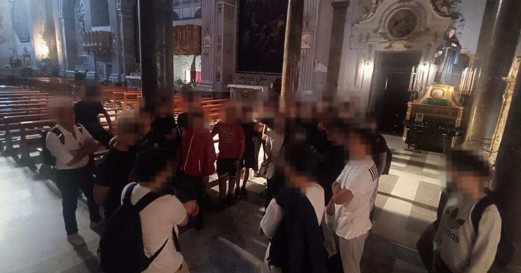 Un gruppo di studenti in cerchio nella navata di una chiesa durante un'uscita del progetto; i volti sono sfocati